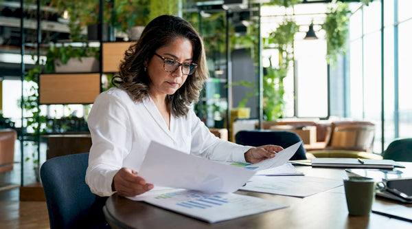 Businesswoman reviewing financial documents at office table