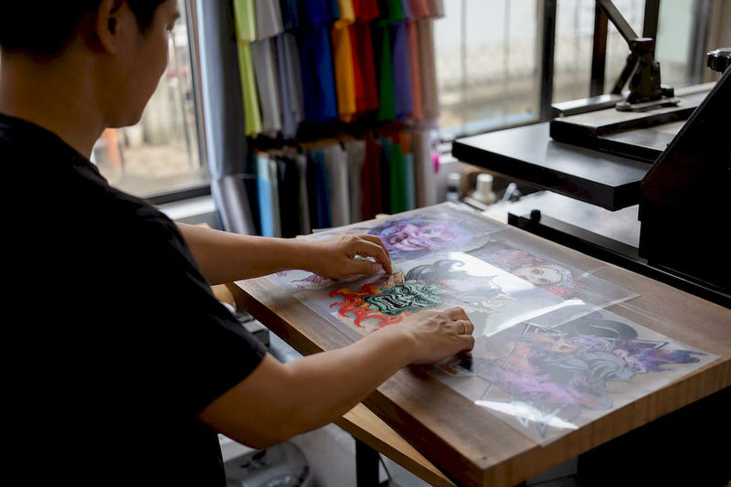 Hands arranging colorful DTF gang sheets on printer platen